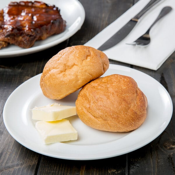 A 10 Strawberry Street Taverno white porcelain bread and butter plate with two rolls of bread and butter.