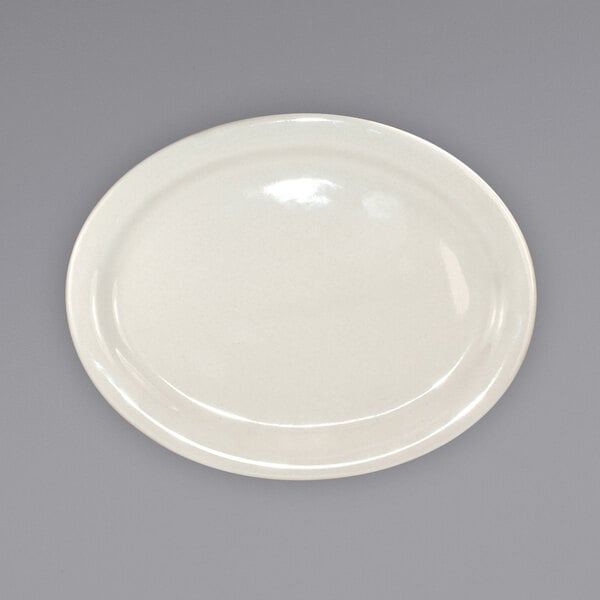 An International Tableware ivory stoneware platter with a narrow rim on a gray surface.