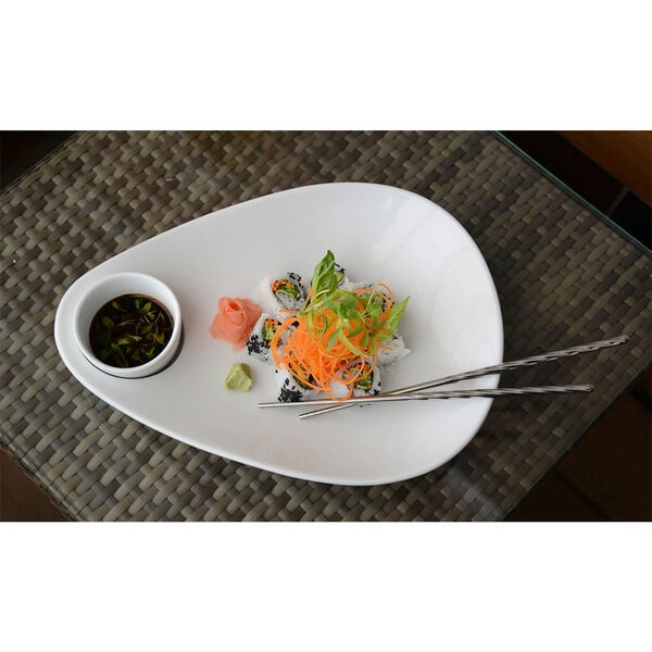 A white plate of sushi with a pair of stainless steel twisted chopsticks and sauce.