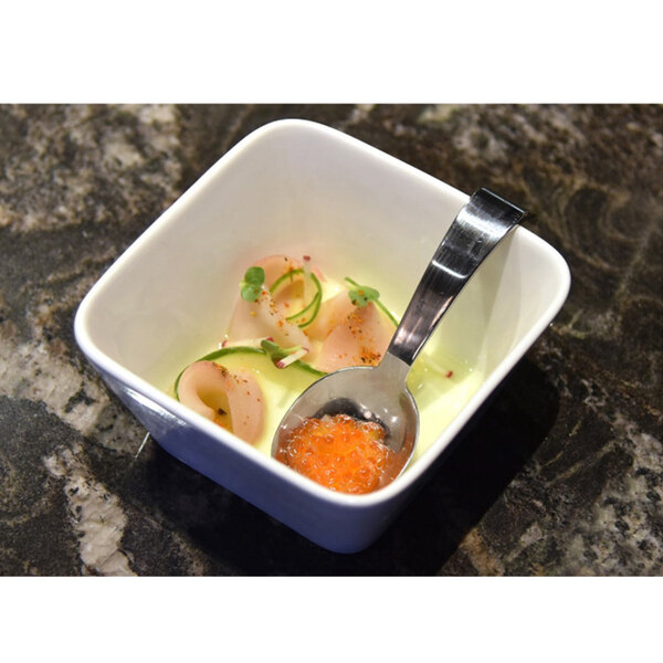 A bowl of food with a stainless steel taster spoon in it.