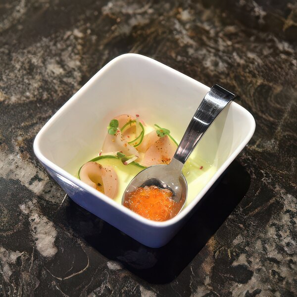 A Front of the House stainless steel taster spoon in a small bowl of food.