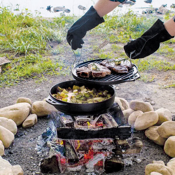 A person using a Lodge Cast Iron Cook-It-All to cook steak on a grill.