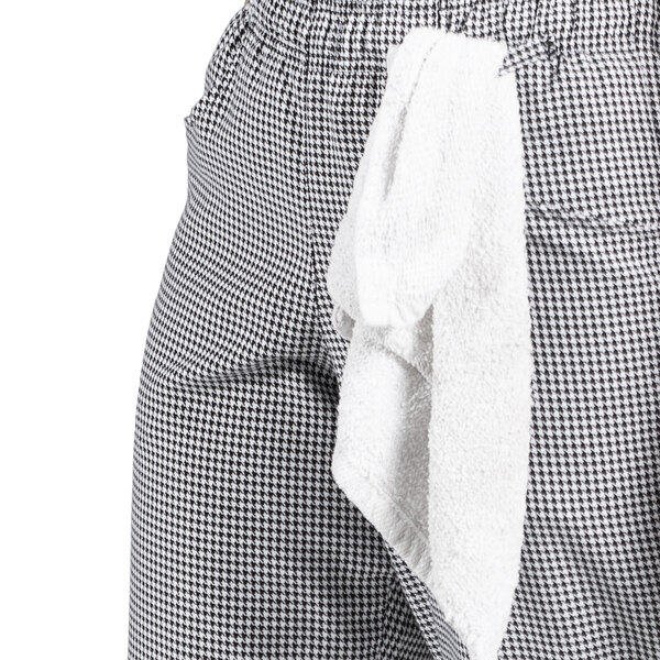 A woman wearing black and white checkered chef pants with a white towel in the pocket.