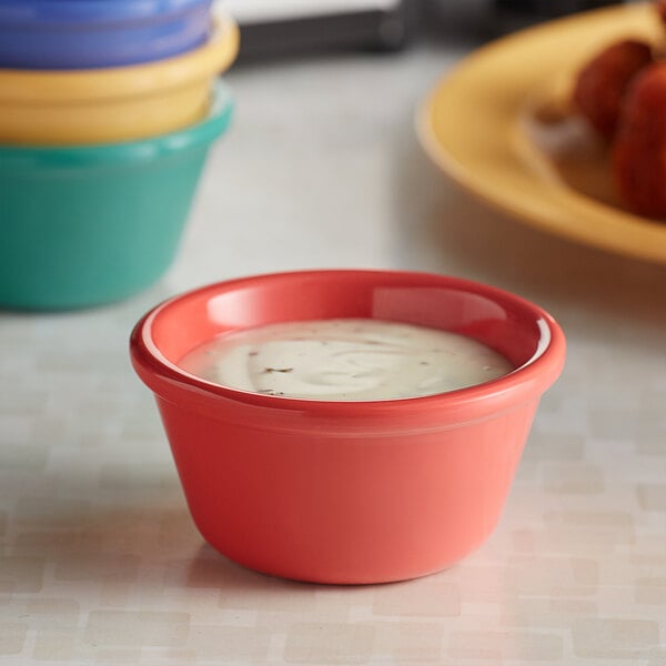 A bowl of food sits on a table next to a stack of colorful ramekins.