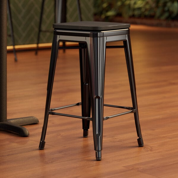 A Lancaster Table & Seating black backless counter height stool with black wood seat.