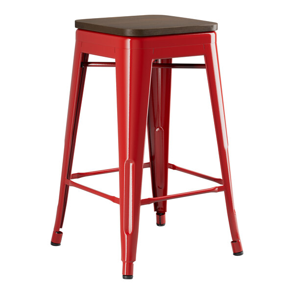 A Lancaster Table & Seating red metal backless counter height stool with a walnut wood seat.