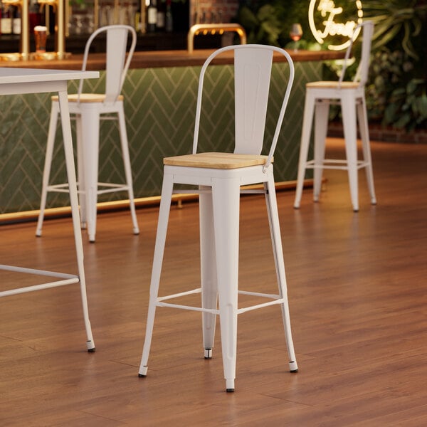 A white Lancaster Table & Seating barstool with a natural wood seat