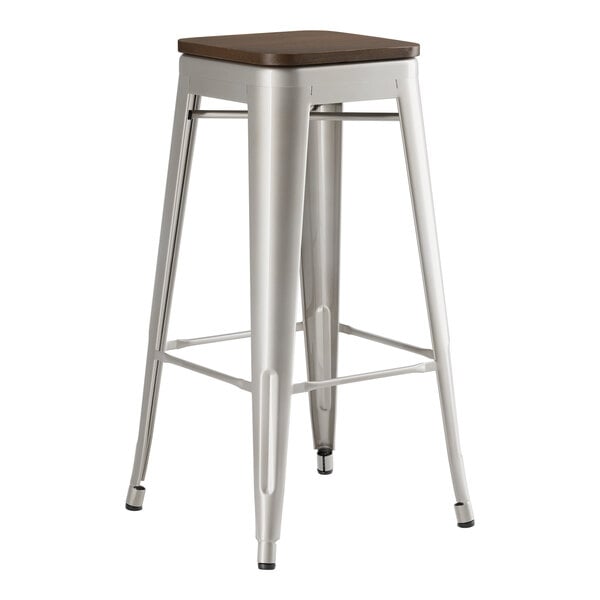 A Lancaster Table & Seating silver metal backless barstool with a walnut wood seat.
