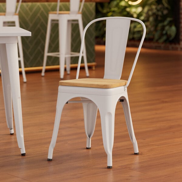 A white Lancaster Table & Seating metal chair with a natural wood seat at a table.