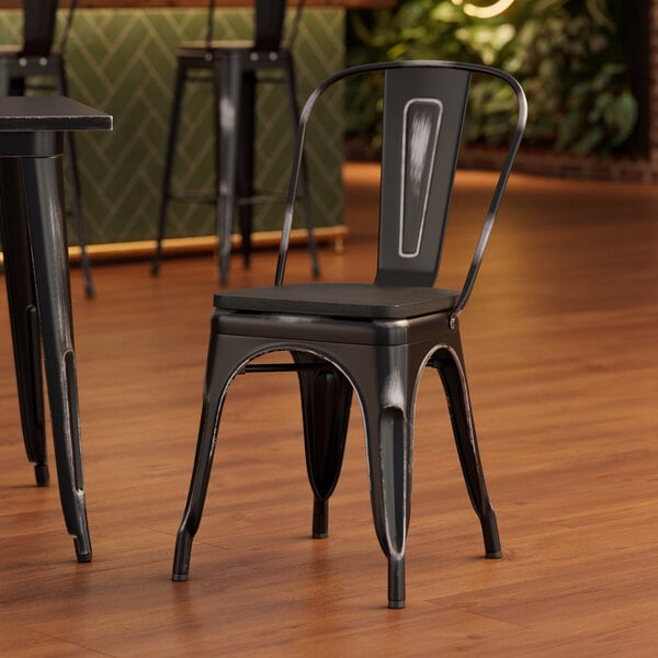 A Lancaster Table & Seating black metal chair with a black wood seat at a table in a restaurant.