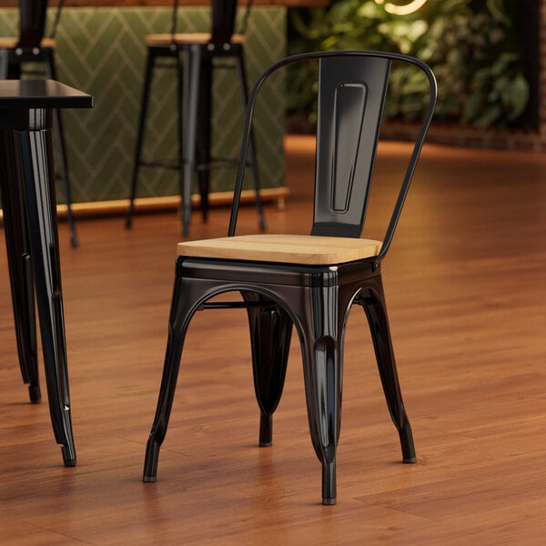 A Lancaster Table & Seating black metal chair with a natural wood seat and back.