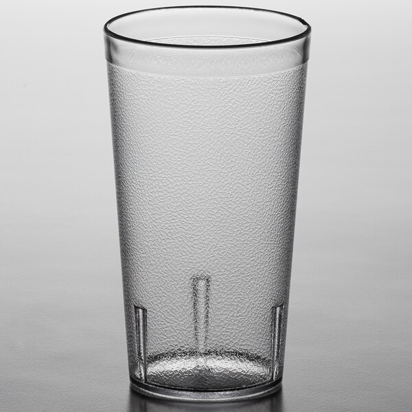 A Carlisle clear plastic tumbler on a table.