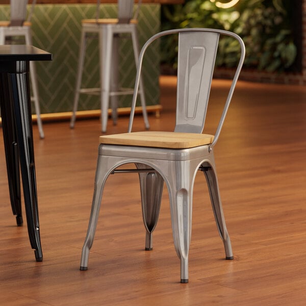 A Lancaster Table & Seating metal chair with a natural wood seat at a table in a coffee shop.