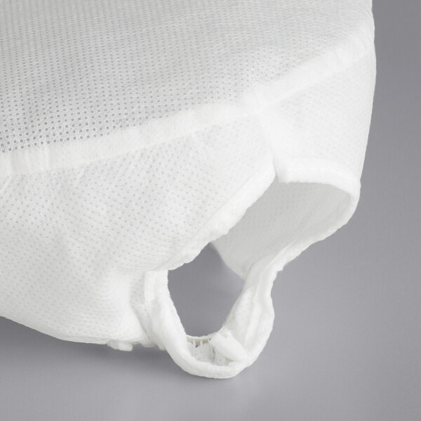 A white AmerCare Royal beanie chef cap in a plastic bag with a hole in it.