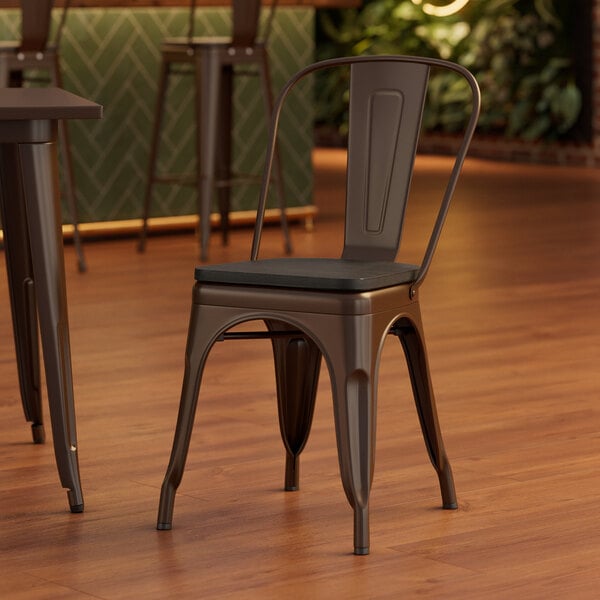 A Lancaster Table & Seating brown metal chair with a black wood seat at a table.