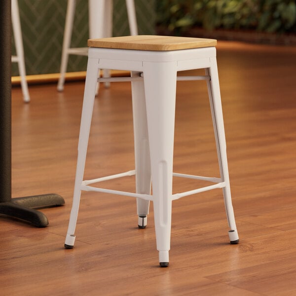 A white Lancaster Table & Seating backless counter height stool with a natural wood seat.