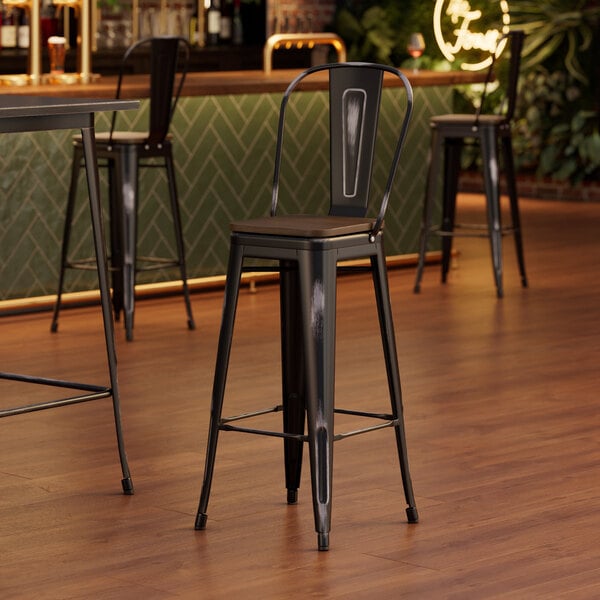 A Lancaster Table & Seating black barstool with a walnut wood seat.