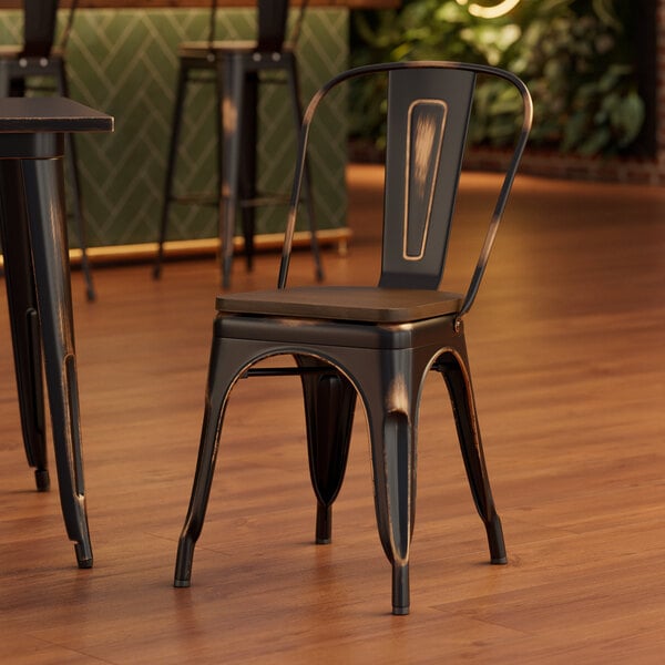 A Lancaster Table & Seating distressed copper metal chair with a walnut wood seat at a table in a restaurant.