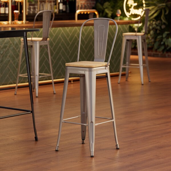 A Lancaster Table & Seating barstool with a natural wood seat and metal legs.