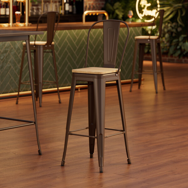 A Lancaster Table & Seating copper barstool with a natural wood seat at a wooden table in a bar