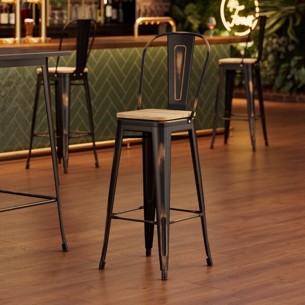 A Lancaster Table & Seating barstool with a natural wood seat at a table in a bar.