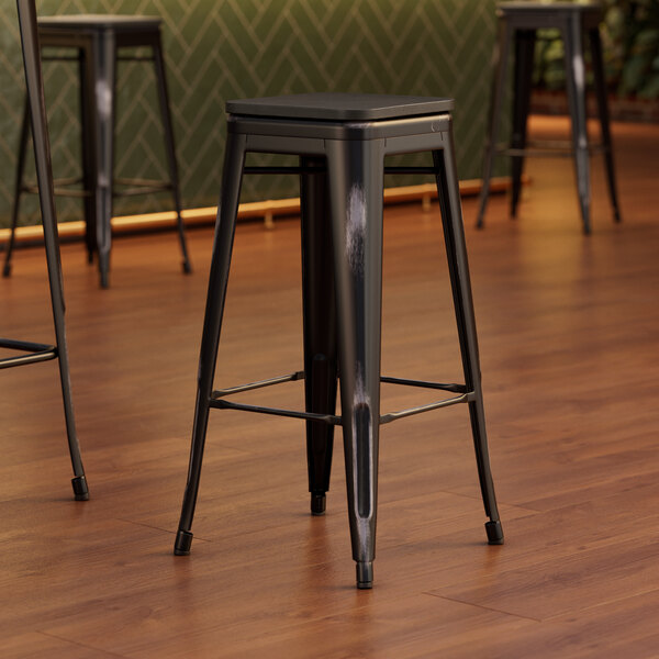 Three Lancaster Table & Seating black metal bar stools with black wood seats.