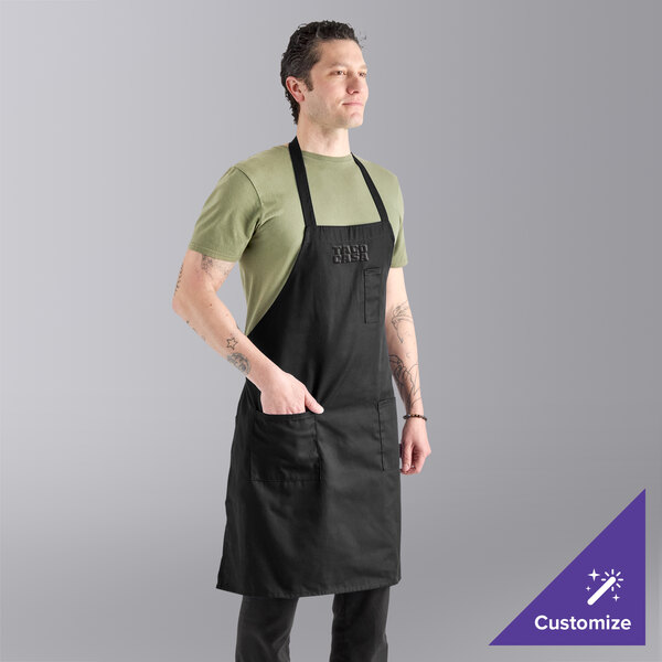A black poly-cotton twill bib apron with three pockets, shown being worn by a person.