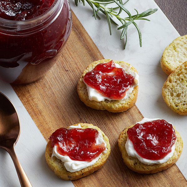 A jar of Dalmatia Organic Strawberry Spread with a spoon on a white background.