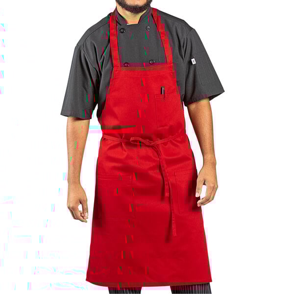 A man wearing a red Uncommon Chef bib apron with black pants.