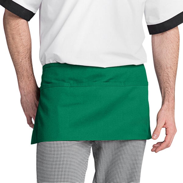 A man wearing a Uncommon Chef Kelly Green waist apron with pockets.