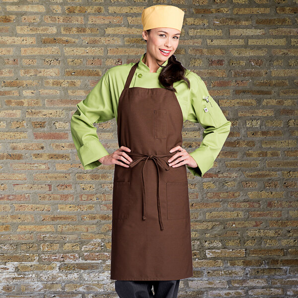 A woman wearing a brown Uncommon Chef bib apron with pockets.