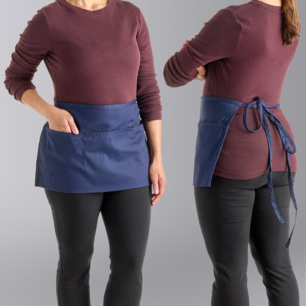 A woman wearing a navy blue Uncommon Chef waist apron with three pockets.