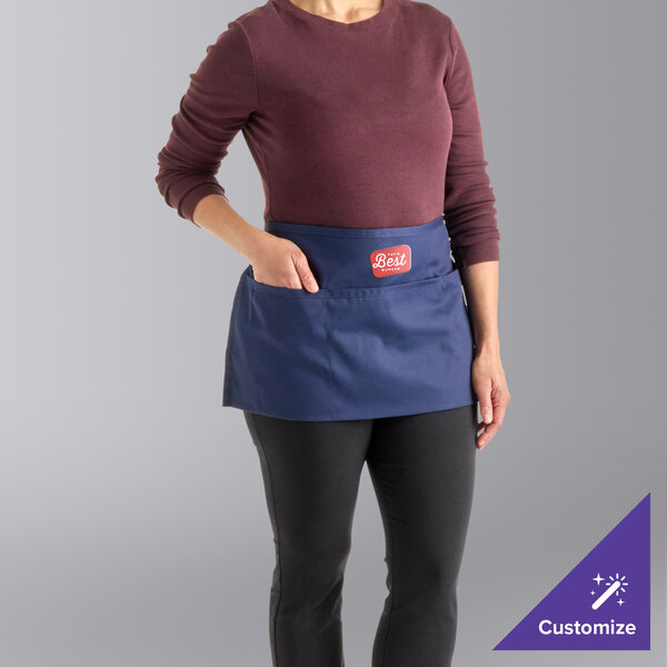 A navy blue customizable waist apron with three pockets, worn around the waist.