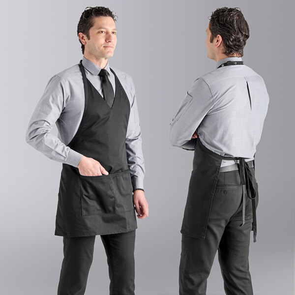 Two men wearing black Uncommon Chef tuxedo aprons standing in a professional kitchen.