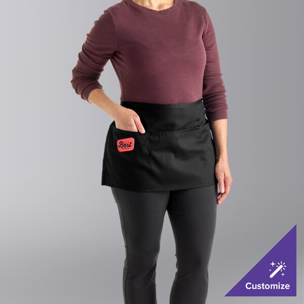 A black customizable waist apron with three pockets, worn by a person.