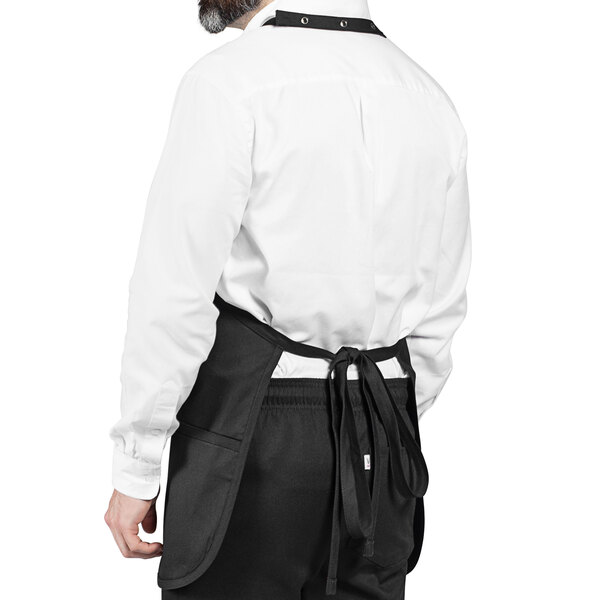 A man wearing a white shirt and black Uncommon Chef Tuxedo apron.