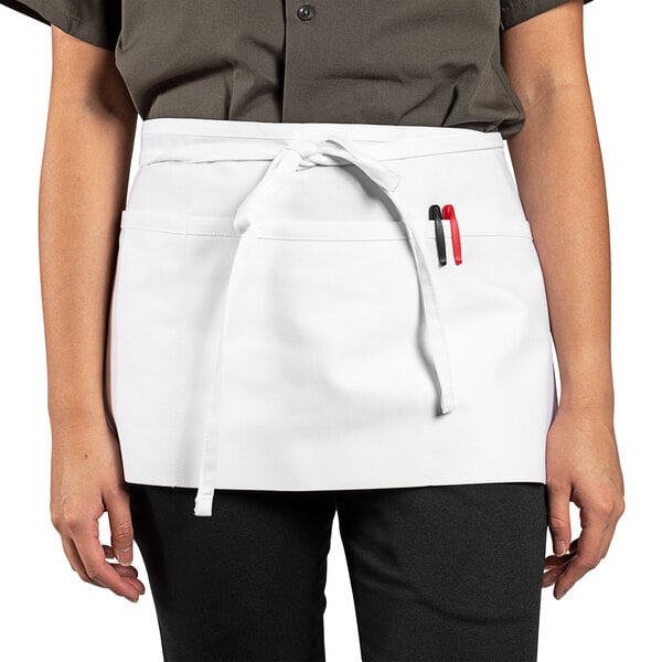 A woman wearing a white Uncommon Chef waist apron with three pockets.