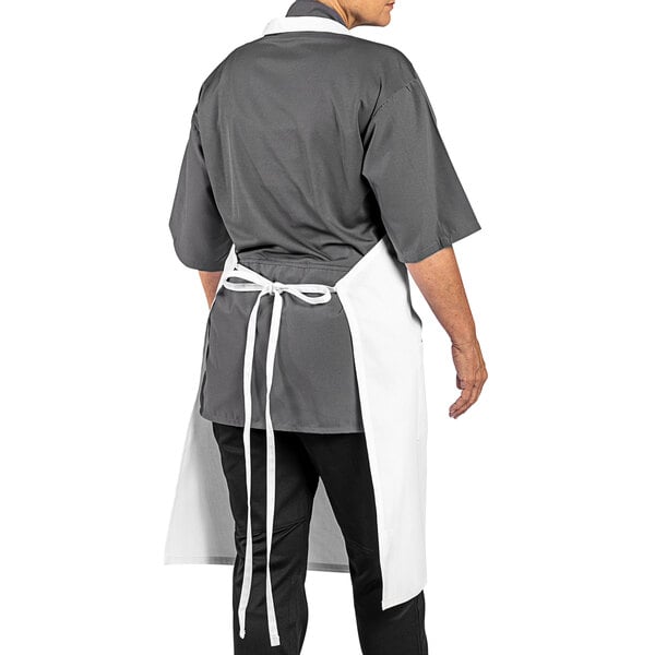 A man wearing a white Uncommon Chef bib apron with grey trim and pockets.
