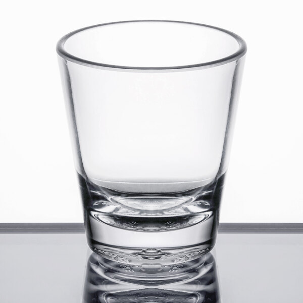 A Carlisle clear plastic shot glass on a table.