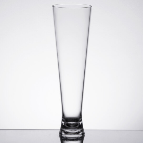 A Carlisle clear plastic pilsner glass on a table.