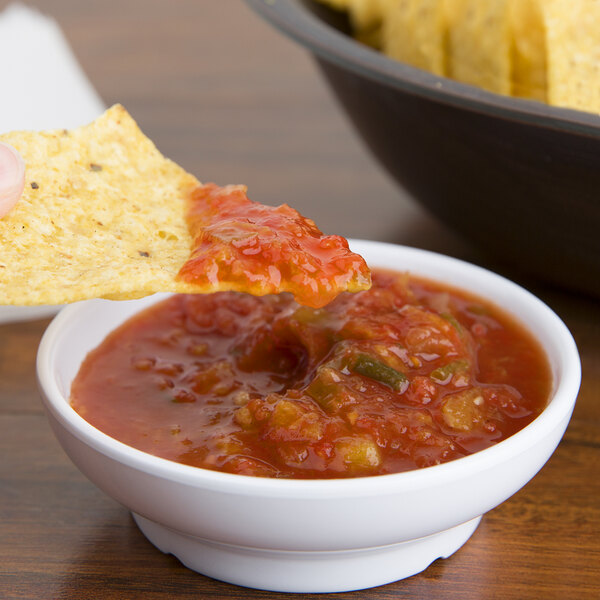 A chip being dipped into a white GET salsa bowl.