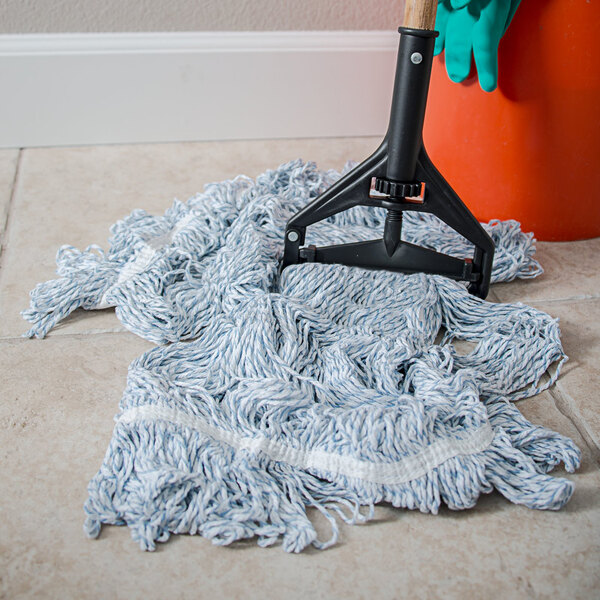 A Carlisle blue wet mop with a black handle on the floor.