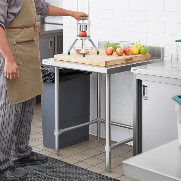 A man using a Regency stainless steel work table in a kitchen.