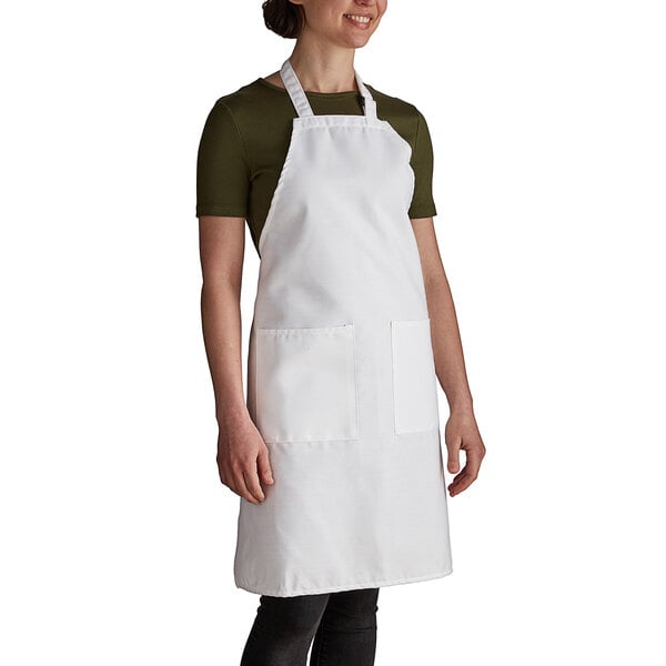 A woman wearing a white Intedge bib apron with two pockets.