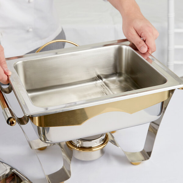 A person holding a stainless steel water pan for a chafer.