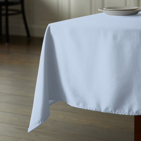 A square table with a light blue Intedge tablecloth on it.