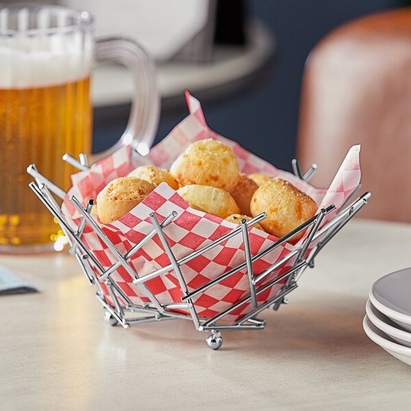 An American Metalcraft round chrome basket filled with french fries on a table in a pizza parlor.