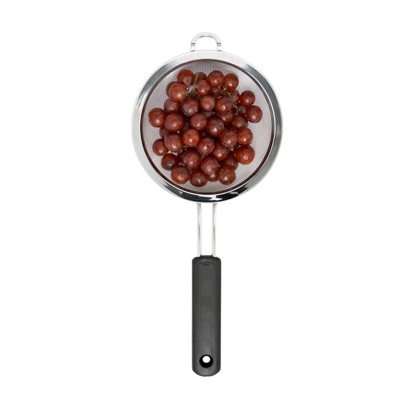 A OXO stainless steel strainer with grapes in it.