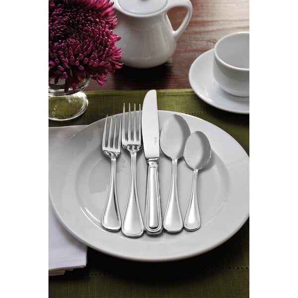 A white plate with a Sant'Andrea Bellini stainless steel salad/dessert fork on it, next to a flower.