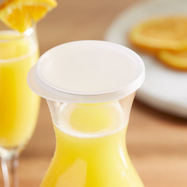 A glass of yellow liquid with a white lid on a white background.